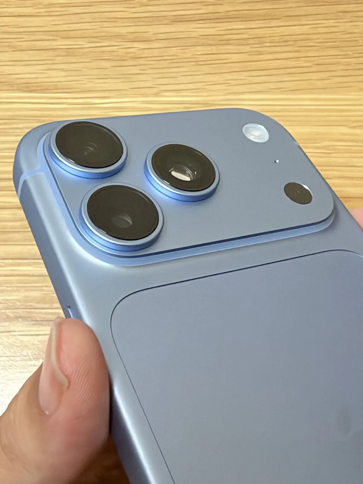iPhone 18 Pro（グレイシャー）のカメラ部を手に持って接写した写真。48MPの3眼レンズ、フラッシュ、LiDAR、マイク